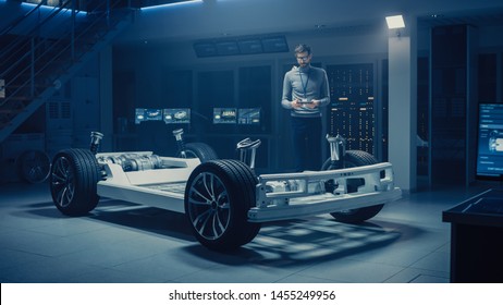 Automobile Engineer Work On Electric Car Platform Chassis Prototype, Using Tablet Computer With 3D CAD Software Modelling. Innovative Facility: Vehicle Frame With Wheels, Engine,Battery And Suspension