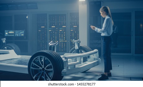 Automobile Engineer Working on Electric Car Chassis Platform, Using Tablet Computer Augmented Reality with 3D CAD Software Modelling. Innovative Facility: Vehicle Frame with Wheels, Engine, Battery - Powered by Shutterstock