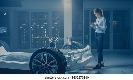 Automobile Engineer Working on Electric Car Chassis Platform, Using Tablet Computer Augmented Reality with 3D CAD Software Modelling. Innovative Facility: Vehicle Frame with Wheels, Engine, Battery - Powered by Shutterstock