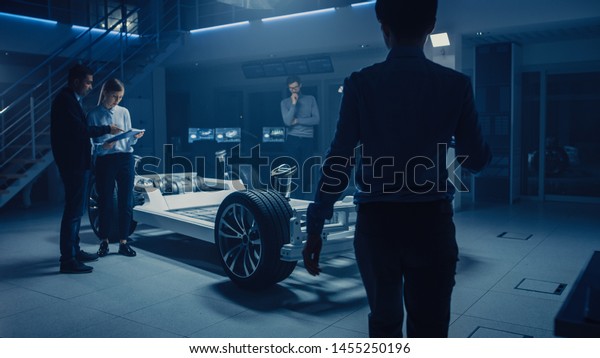Automobile Engineers Designing Electric Car\
Platform Chassis Prototype, Using Tablet Computers with CAD\
Software for 3D Concept. In Automotive Innovation Facility Vehicle\
Frame with Wheels,\
Engine
