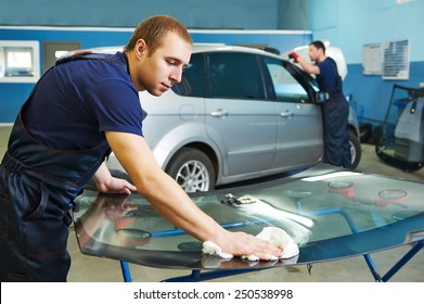 Automobile glazier adding glue on windscreen or windshield of a car in auto service station garage before installation