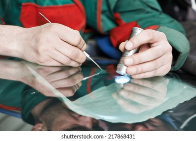 Automobile glazier worker fixing and repair windscreen or windshield of a car in auto service station garage - Powered by Shutterstock