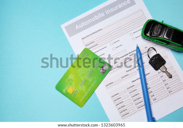 Automobile insurance form with credit card and\
car key on color\
background