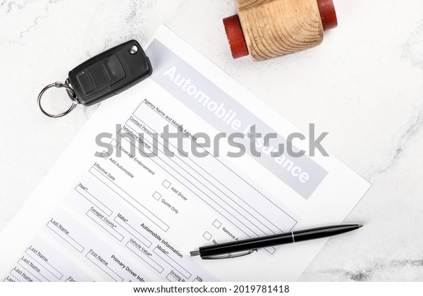 Automobile insurance with key and car figure on\
light background,\
closeup