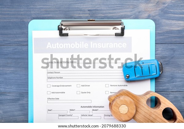 Automobile insurance with key and car figure\
on color wooden\
background