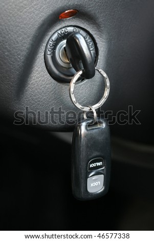 Automobile key with a charm inserted into the lock of ignition of the car