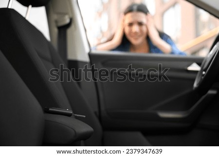 Automobile lockout, key forgotten inside, selective focus. Emotional woman looking through car window