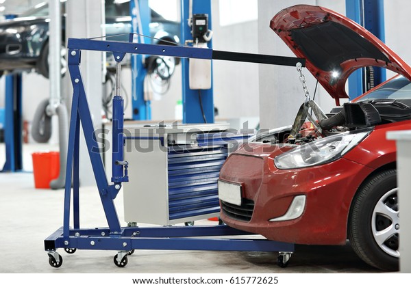 automobile mechanic a crane removed the\
engine from the car. repairing auto in automobile\
store