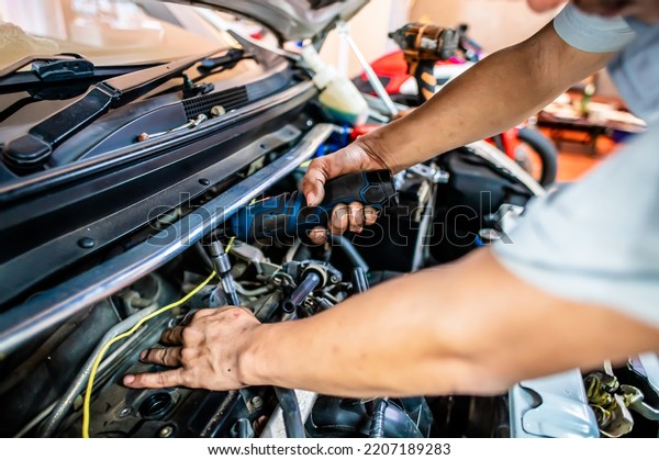 Automobile mechanic repairman hands\
repairing a car engine automotive workshop with modern\
tools.