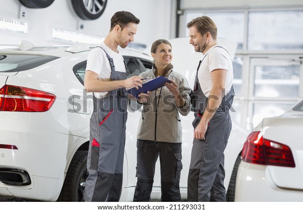 Automobile mechanics discussing over clipboard in\
car repair shop
