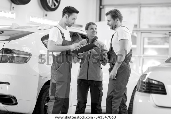 Automobile mechanics discussing over clipboard in
car repair shop