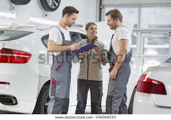 Automobile mechanics discussing over clipboard in\
car repair shop