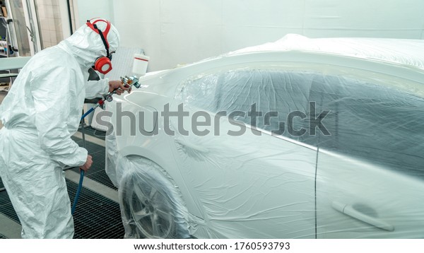 Automobile painting. Car painter with gun in\
chamber. Spray\
operation.