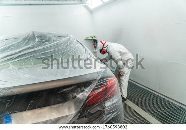 Automobile painting. Car painter with gun in\
chamber. Spray\
operation.