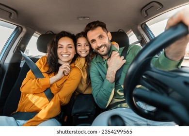 Alquiler y compra de automóviles. Una familia emocionada que se siente sentada en un coche nuevo conduciendo y disfrutando de un viaje por carretera en vacaciones. Padres e hijas posando y sonriendo a la cámara en auto