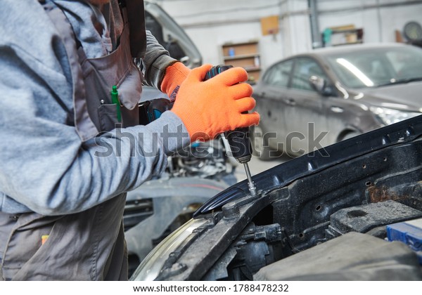 automobile repair\
shop. Worker assembling car\
body
