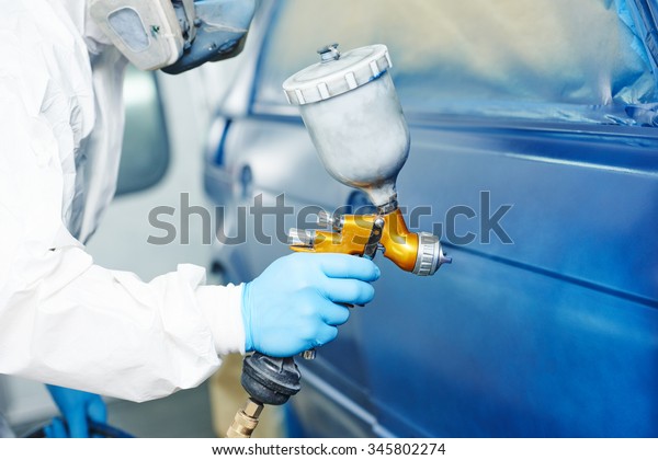 automobile repairman\
painter hand in protective glove with airbrush pulverizer painting\
car body in paint\
chamber