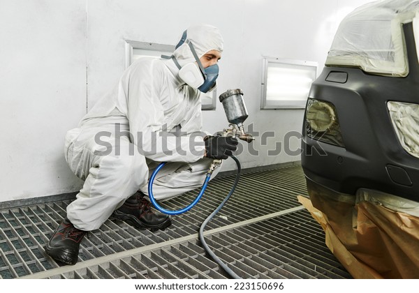 automobile repairman painter painting car body\
bumper in chamber