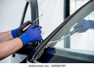 Automobile Special Workers Remove Old Windscreen Or Windshield Of A Car In Auto Service Station Garage. Background