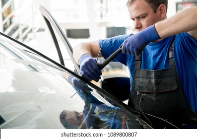 Automobile Special Workers Remove Old Windscreen Or Windshield Of A Car In Auto Service Station Garage. Background