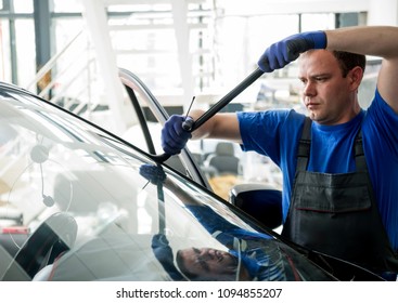 Automobile Special Workers Remove Old Windscreen Or Windshield Of A Car In Auto Service Station Garage. Background