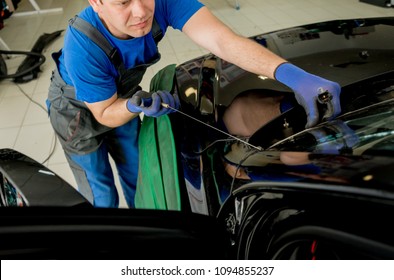 Automobile Special Workers Remove Old Windscreen Or Windshield Of A Car In Auto Service Station Garage. Background