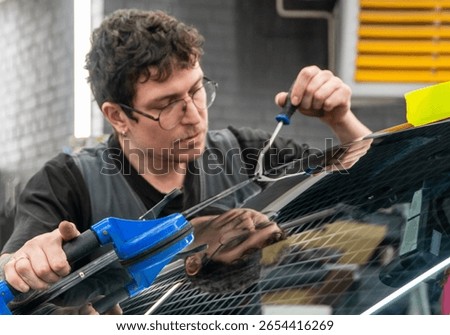 Automobile special workers replacing windscreen or windshield of a car in auto service station garage. Glass of the car, removed with the help of professional suction cups. The process of car repair. 