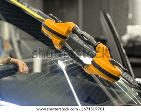 Automobile special workers replacing windscreen or windshield of a car in auto service station garage. Glass of the car, removed with the help of professional suction cups. The process of car repair. 