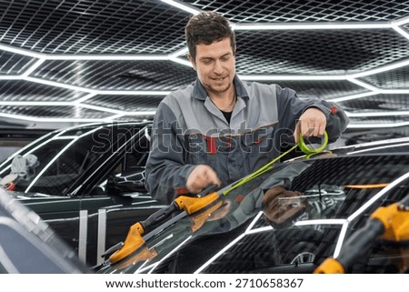 Automobile special workers replacing windscreen or windshield of a car in auto service station garage. Glass of the car, removed with the help of professional suction cups. The process of car repair. 