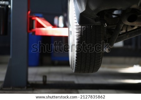 Automobile tire, part of automobile in service center, lifted car in air