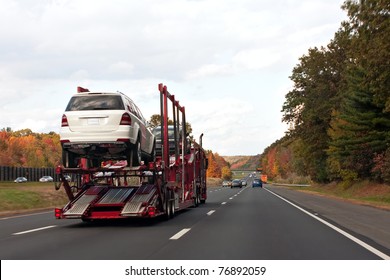 An automotive car carrier truck driving down the highway with a full load of new vehicles.