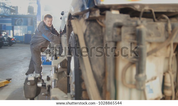 Automotive car repair - worker is moving\
vehicle for wheel\'s collapse of\
convergence