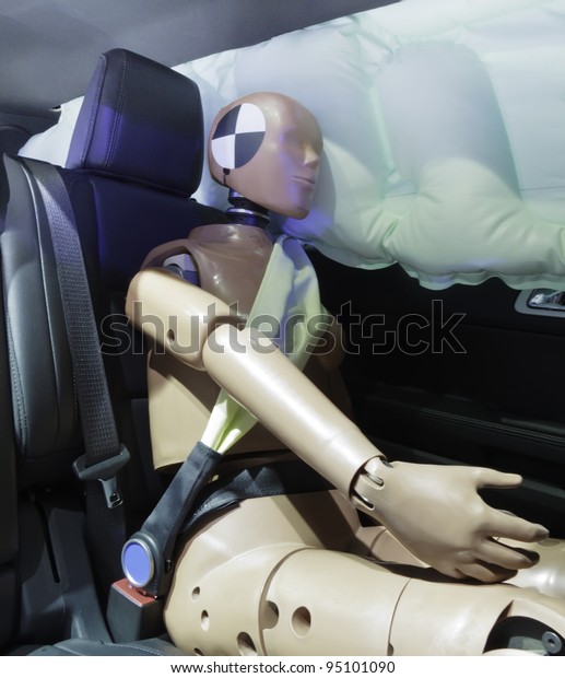 Automotive crash test dummy strapped into car seat,\
head against air bag