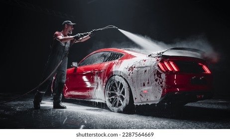 Automotive Detailer Washing Away Smart Soap and Foam with a Water High Pressure Washer. Red Performance Car Getting Care and Treatment at a Professional Vehicle Detailing Shop - Shutterstock ID 2287564669