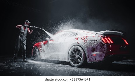 Automotive Detailer Washing Away Smart Soap and Foam with a Water High Pressure Washer. Red Performance Car Getting Care and Treatment at a Professional Vehicle Detailing Shop - Shutterstock ID 2287564671