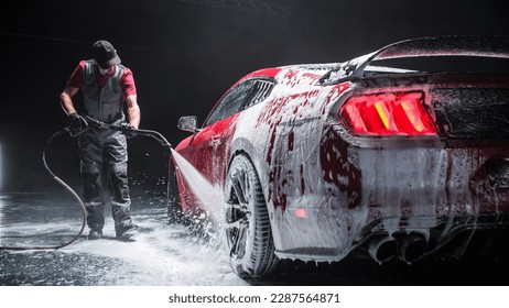 Automotive Detailer Washing Away Smart Soap and Foam with a Water High Pressure Washer. Close Up of a Red Performance Car Getting Care and Treatment at a Professional Vehicle Detailing Shop - Shutterstock ID 2287564871
