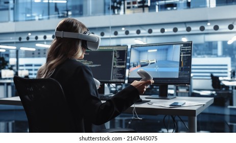 Automotive Engineer Using A VR Software To Work On Electric Motor And Vehicle Platform In Interactive Environment In A Factory Office. Industrial Engineer Using Headset And Controllers.