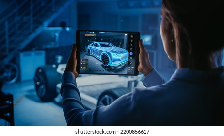 Automotive Engineer Working on Electric Car Chassis Platform, Using Tablet with Augmented Reality 3D Software. Innovative Facility Concept: Vehicle Frame with Wheels Becomes a VFX Virtual Model. - Shutterstock ID 2200856617