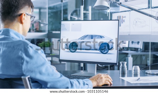 Automotive Engineer Works on the Personal\
Computer, He Perfects New Car Model Prototype Sketch. He Works in\
the Bright and Modern\
Office.