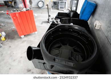 An automotive garage interior featuring a black oil collection pan, red toolbox, and various tools. Ideal for concepts of mechanics, repair, and vehicle maintenance. - Powered by Shutterstock