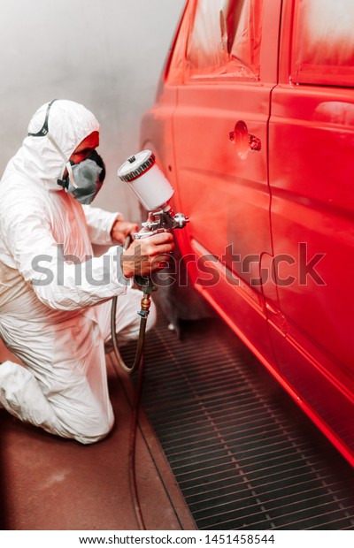 Automotive industry manufacturing details\
- painter working on applying red paint on a\
van