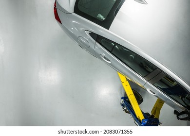 Automotive Industry Theme. Modern Silver Compact Car On A Lift Inside An Auto Service. Vehicle Repair And Maintenance