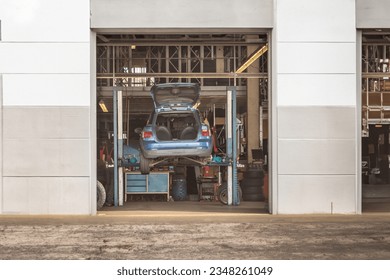 Automotive Maintenance: Car on Lifting Platform in Garage for Repairs and Inspection, Mechanic's Workshop with Elevated Vehicle - Powered by Shutterstock