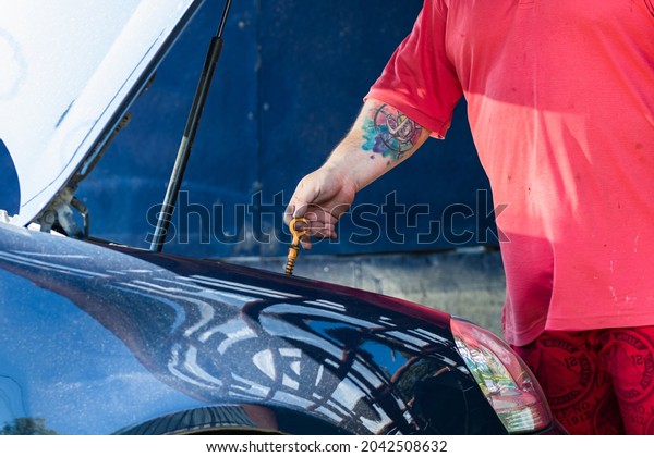 Automotive
mechanic checking the level of engine oil. Vehicle maintenance in
the garage in Bucharest, Romania,
2020