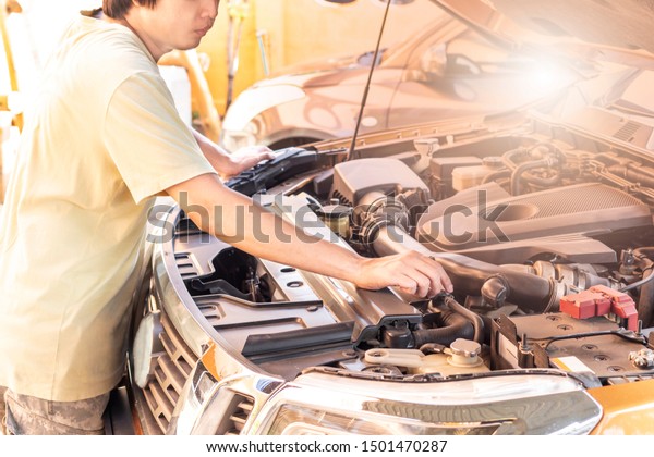 Automotive\
mechanic checking and repair car in\
garage.