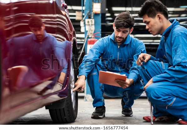 automotive mechanic men checking at car tyre\
rubber condition needed for replacement, man pointing hand at wheel\
following maintenance checklist document, after service at auto\
repair shop concept
