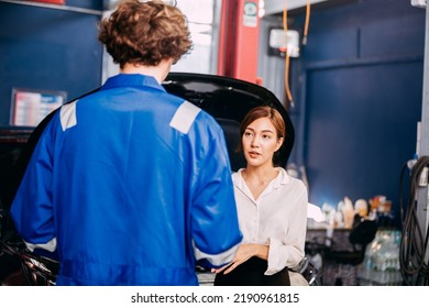 Automotive Mechanic Repairman Talking To Female Customer At The Garage, Check The Mileage Of The Car, Oil Change, Auto Repair Service Concept.