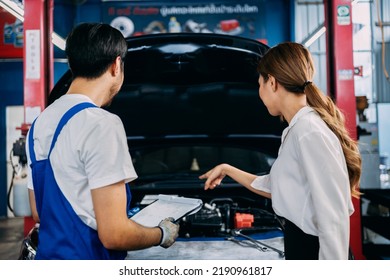 Automotive Mechanic Repairman Talking And Show The Car Checking List Before Fix To Female Customer At The Garage, Check The Mileage Of The Car, Oil Change, Auto Repair Service Concept.