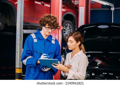 Automotive Mechanic Repairman Talking And Show The Car Checking List Before Fix To Female Customer At The Garage, Check The Mileage Of The Car, Oil Change, Auto Repair Service Concept.