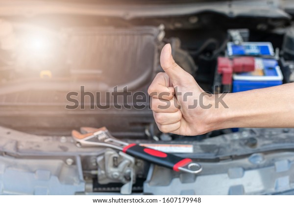 Automotive mechanic show a thumbs up after the\
car check and repair in\
workshop.